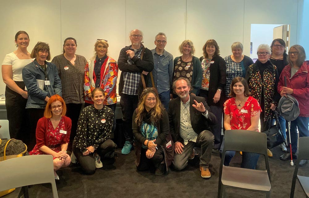 16 members of the Arts For All Taranaki Network pose for a photo with Katie Querin, front right